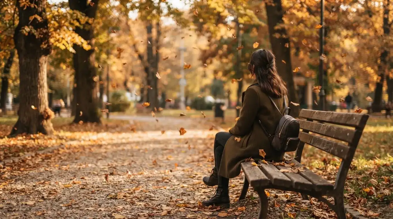 Un om pe o bancă din parc privește frunzele toamnei căzând, în lumină blândă — cazinouri fără licență în românia